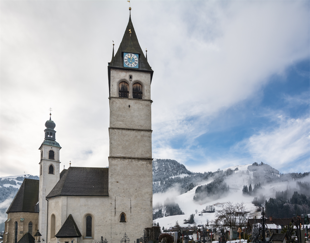 Die Pfarrkirche und die Liebfrauenkirche in Kitzbühel im Winter, dahinter der verschneite Hahnenkamm
